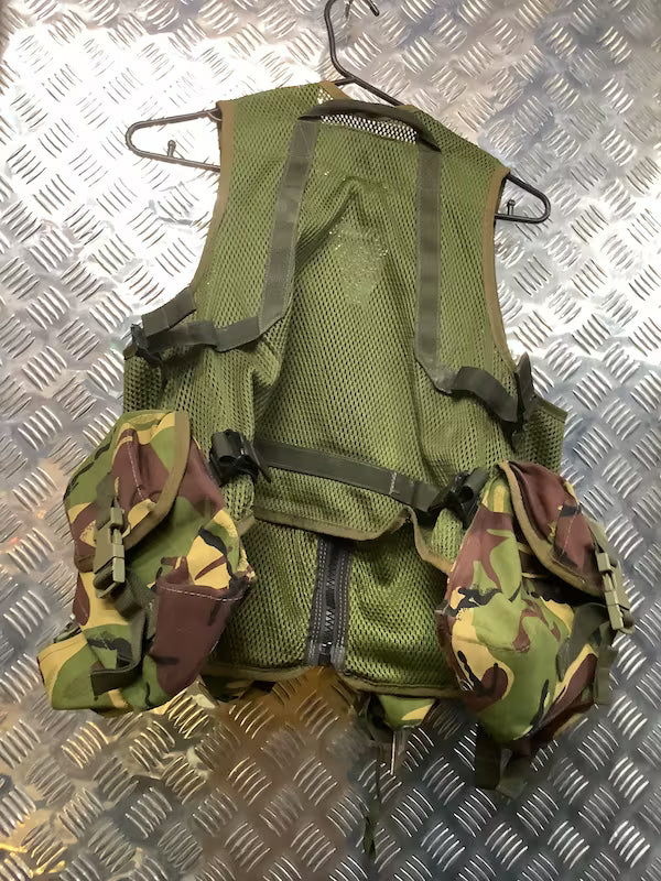 Green tactical vest with camouflage pouches on a metallic surface