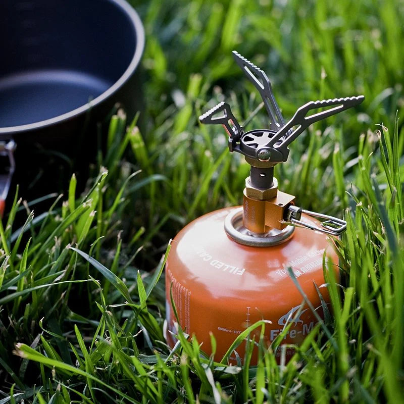 Propane tank on grass with camping pot in the background