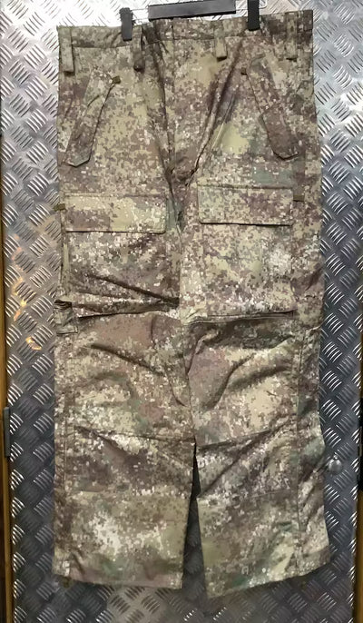 Camouflage military-style pants on a textured metal surface