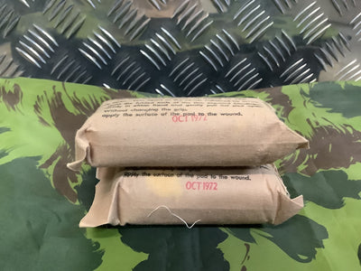 Two wrapped bandages with text on a camouflage-patterned surface