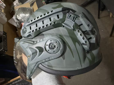 Camouflage helmet with intricate design held by a person in an indoor setting