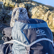 Person wearing a blue Highlander backpack with a hood in a rocky outdoor setting
