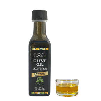 Bottle of Neudorf Black Olive Oil with a glass of olive oil on a white background