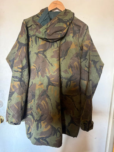 Camouflage-patterned jacket on a hanger against a white wall