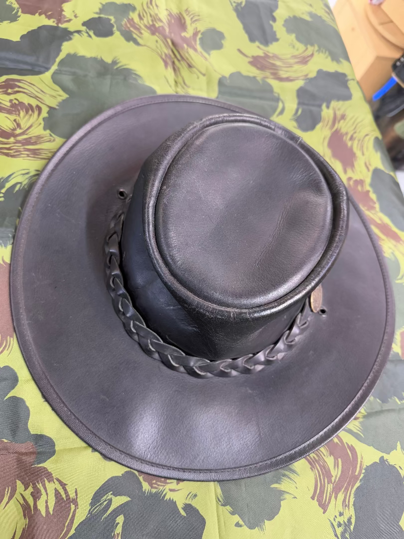Black leather hat with chain detail on a camouflage background
