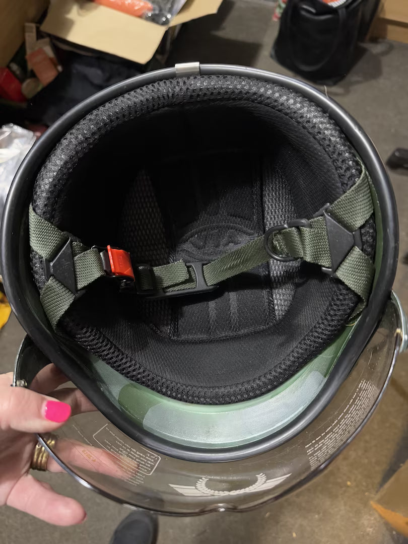 Close-up of a helmet interior with a hand holding it, on a cluttered background.