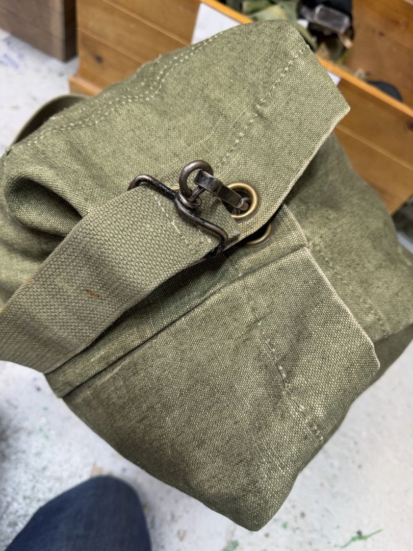 Green fabric bag with a metal clasp on a textured surface