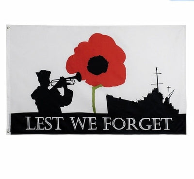 Memorial flag with silhouette of a soldier, red poppy, and ship, featuring 'Lest We Forget' text.