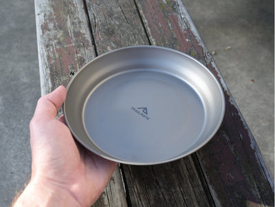 Hand holding a metallic plate with a brand logo on a wooden surface