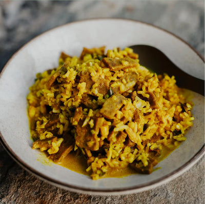 Stir-fried dish with rice and meat in a bowl on a textured surface