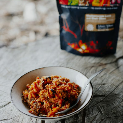 bowl of food with a spoon on a wooden surface, with a package in the background