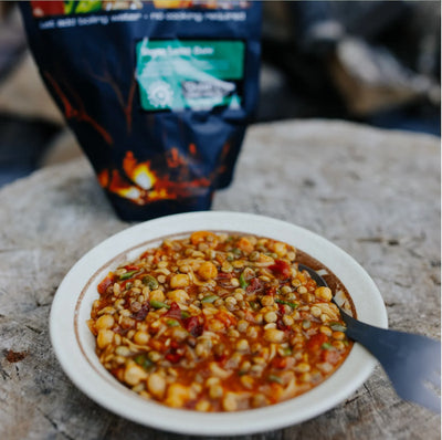 Bowl of food on a stone surface with a backpack in the background