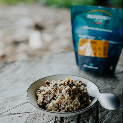 Bowl of food with a spoon on a wooden surface, with a package in the background.