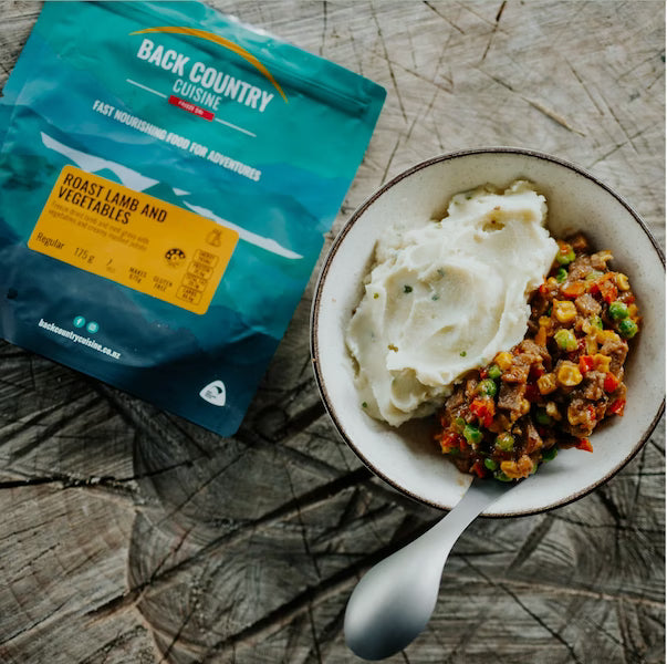 Back Country Cuisine meal package with a bowl of food on a wooden surface