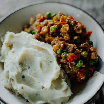 Mashed potatoes with a side of vegetable and meat dish on a plate.
