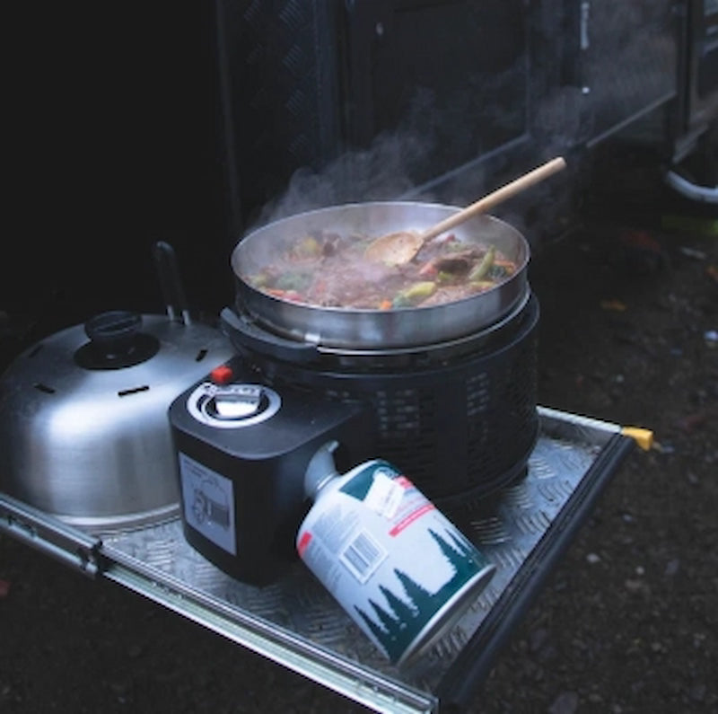 Camping stove with a pot of food on a dark background