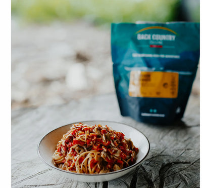 Spaghetti dish on a plate with a Back Country brand package in the background