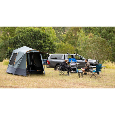 Camping scene with a truck, tent, and people in a natural setting