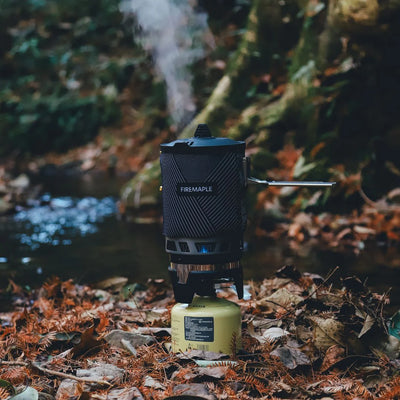 Portable camping stove with fuel canister on forest floor