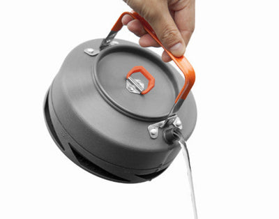 A hand lifting a grey Fire Maple XT1 heat exchanger kettle with an orange handle and lid.