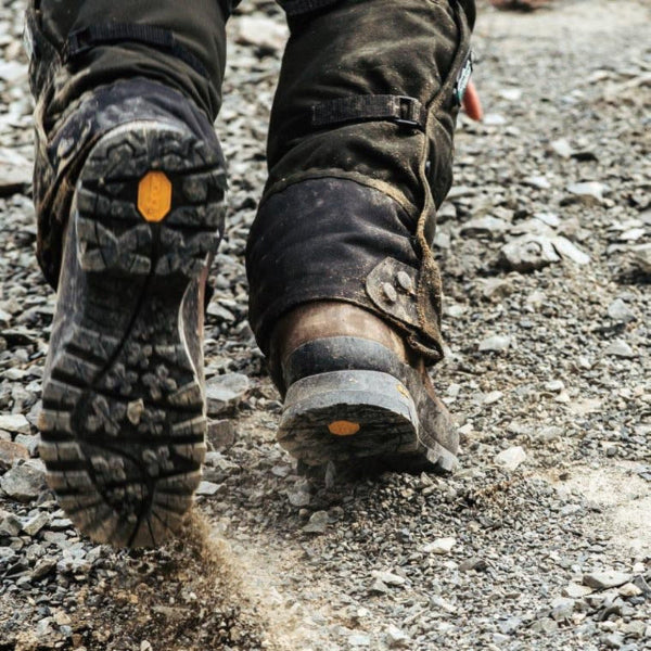 Close-up of a person wearing rugged boots on a rocky ground