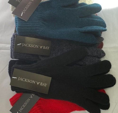 A collection of Jackson Bay wool gloves and beanies in various colors, displayed on a surface with tags attached.
