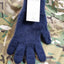 Blue knitted glove with a Kini Dana tag on a camouflage background