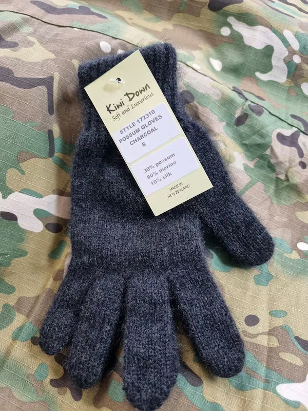 Pair of dark gray gloves with a tag on a camouflage background
