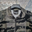 Camouflage jacket on a hanger against a metallic background