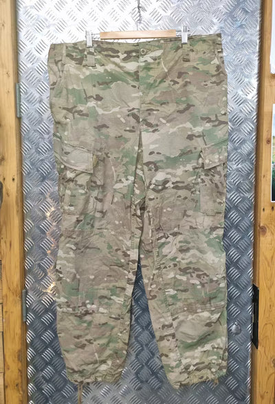 Camouflage pants on a hanger against a metallic background
