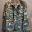 Camouflage jacket on a hanger against a plain background
