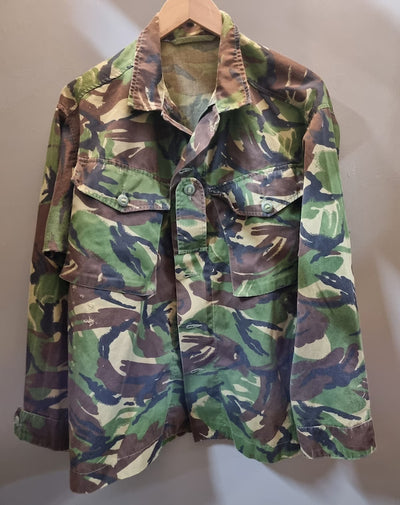 Camouflage jacket on a hanger against a plain background