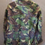 Camouflage jacket on a hanger against a plain background