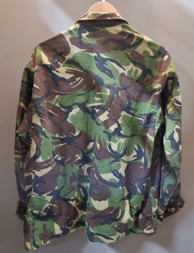 Camouflage jacket on a hanger against a plain background
