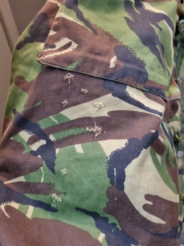 Camouflage-patterned fabric with visible wear and tear