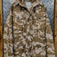 Camouflage jacket on a hanger against a metallic background
