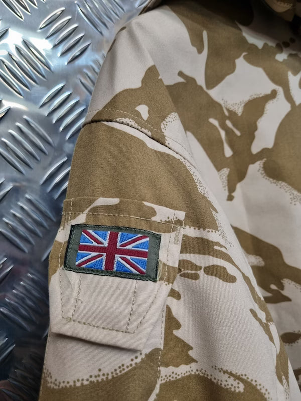 Camouflage military uniform with a British flag patch on an industrial background
