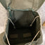 Green backpack with a visible interior on a textured surface
