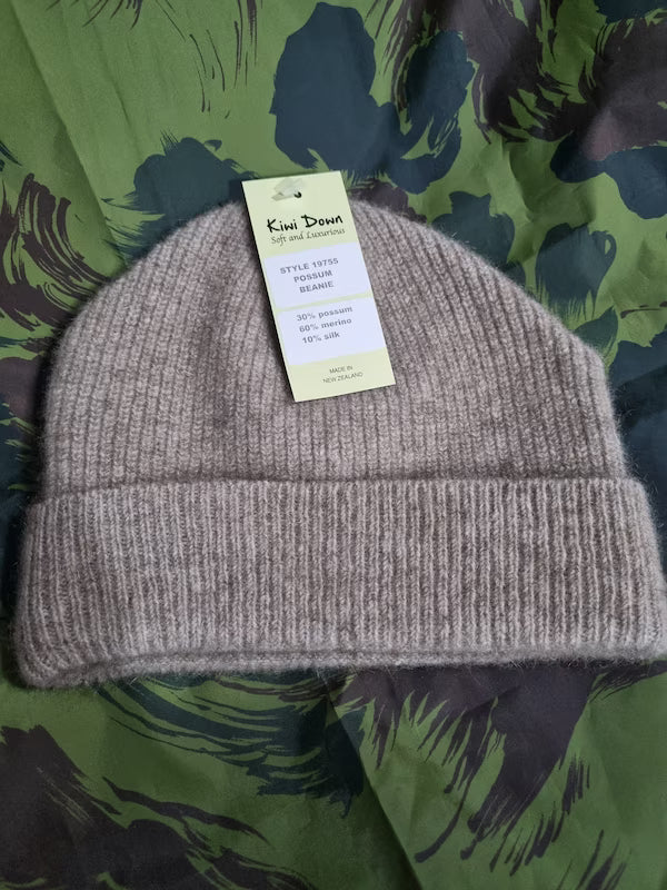 Gray knit beanie with a tag on a green camouflage background