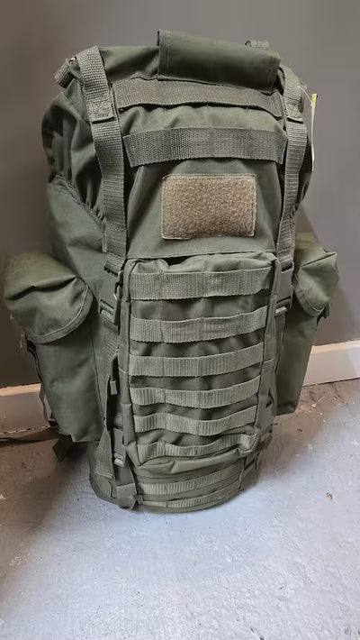 Green tactical backpack on a gray surface with a neutral background