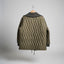 An olive green quilted jacket with a dark gray hood, hanging on a wooden hanger against a diamond plate metal door.