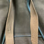 Brown leather strap on a gray bag with blue handle