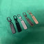 Five keychain fobs of different colors on a green fabric background