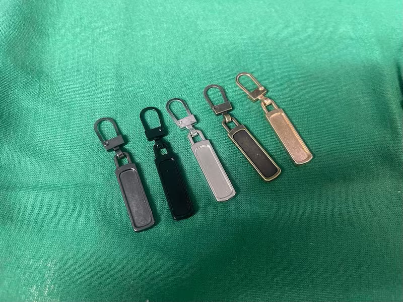 Five keychain fobs of different colors on a green fabric background