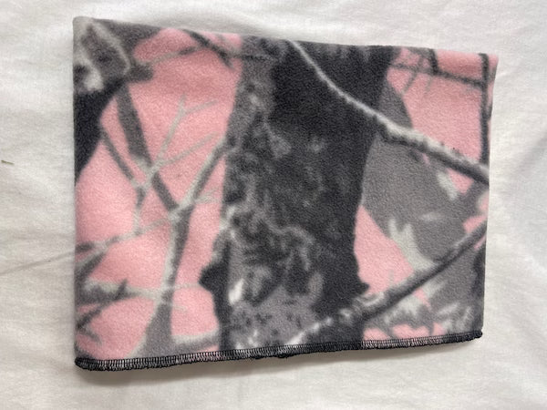 Folded pink and gray camouflage blanket on a white surface