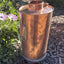 Copper outdoor heater on a garden ground with plants and flowers in the background