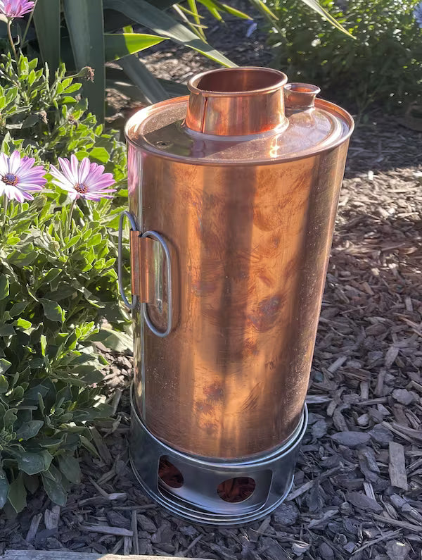 Copper outdoor heater on a garden ground with plants and flowers in the background