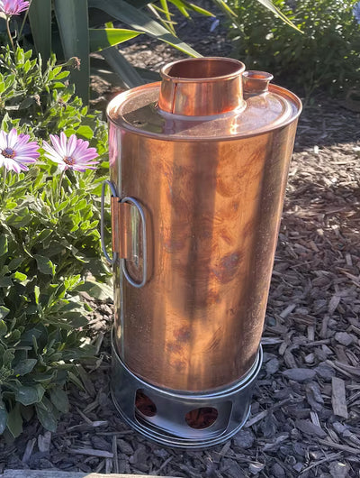 Copper outdoor heater on a garden ground with plants and flowers in the background
