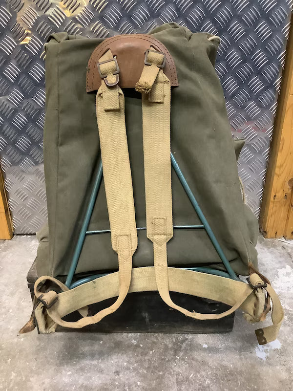 Green backpack with brown straps on a textured surface