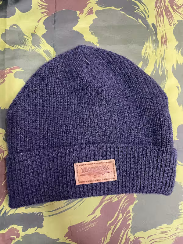 Blue knit beanie with a pink patch on a colorful abstract background